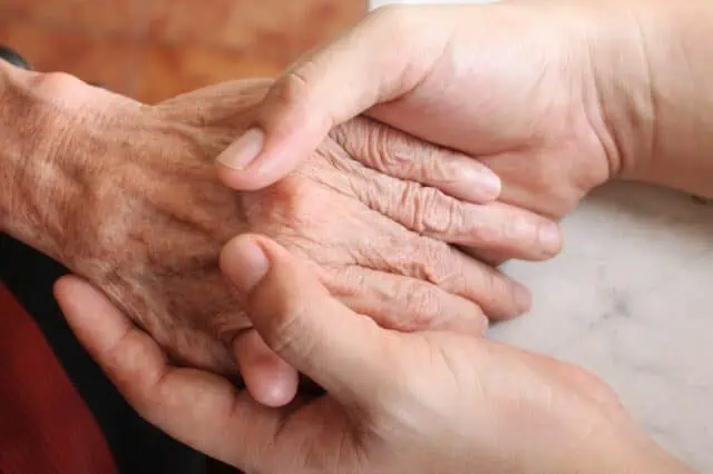 Jüngere Hand hält die Hand einer älteren Person