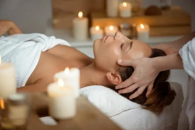 Kopfmassage bei Kerzenlicht auf einer Spa-Liege