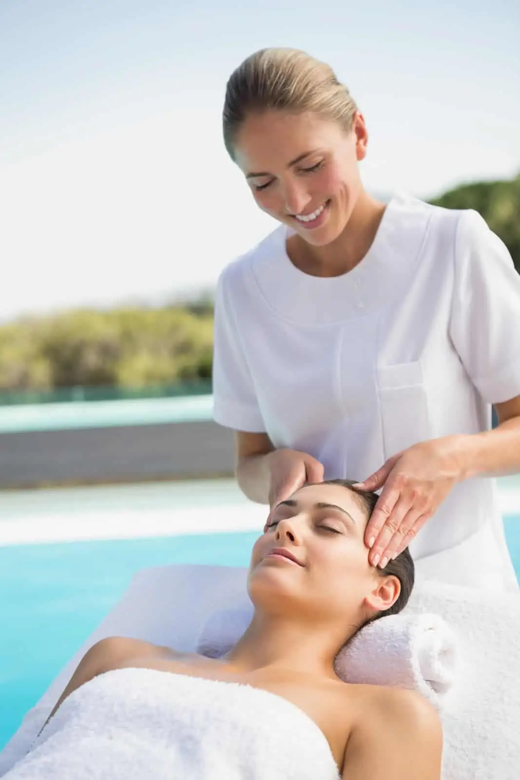 Mitarbeiterin gibt einem Gast eine Kopfmassage im Außenbereich eines Spa