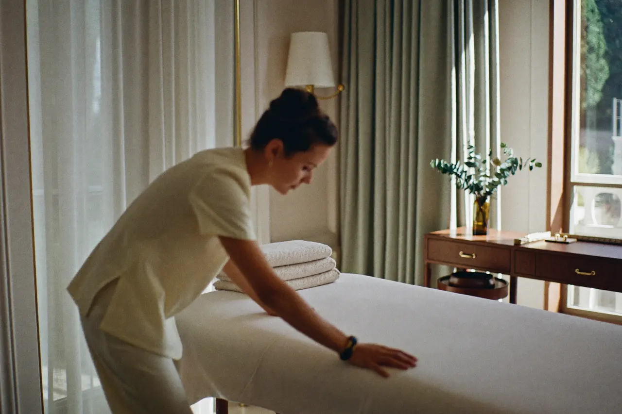 Massagetherapeutin richtet eine Behandlungsliege in einer hellen Hotel-Spa-Suite her